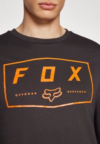 Fekete pamut póló merész narancssárga "FOX" logóval és róka grafikával, "OFFROAD RESEARCH" felirattal téglalap formában.