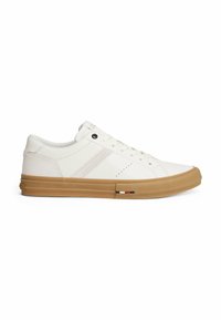 Zapatillas blancas con parte superior sintética suave, suela de goma en color beige, detalles de costura y un elemento decorativo de marca en rojo, blanco y negro.