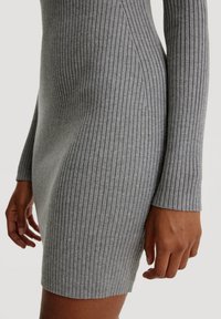 Graues, geripptes Longsleeve-Kleid mit figurbetonter Silhouette. Besitzt einen strukturierten Stoff und einen seitlichen Saum. Die Ärmel sind enganliegend mit Rippdetails.