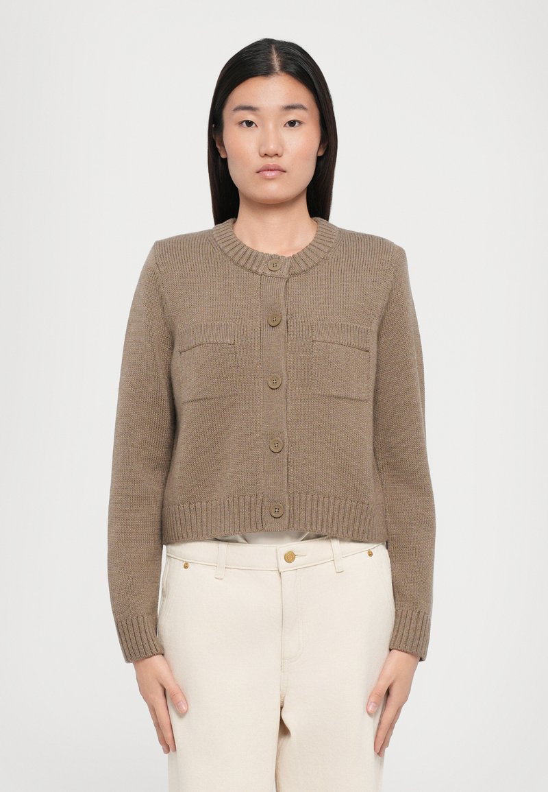 Cardigan corto in tessuto a maglia color taupe con texture a coste, scollo rotondo, sei bottoni frontali e due tasche sul petto.