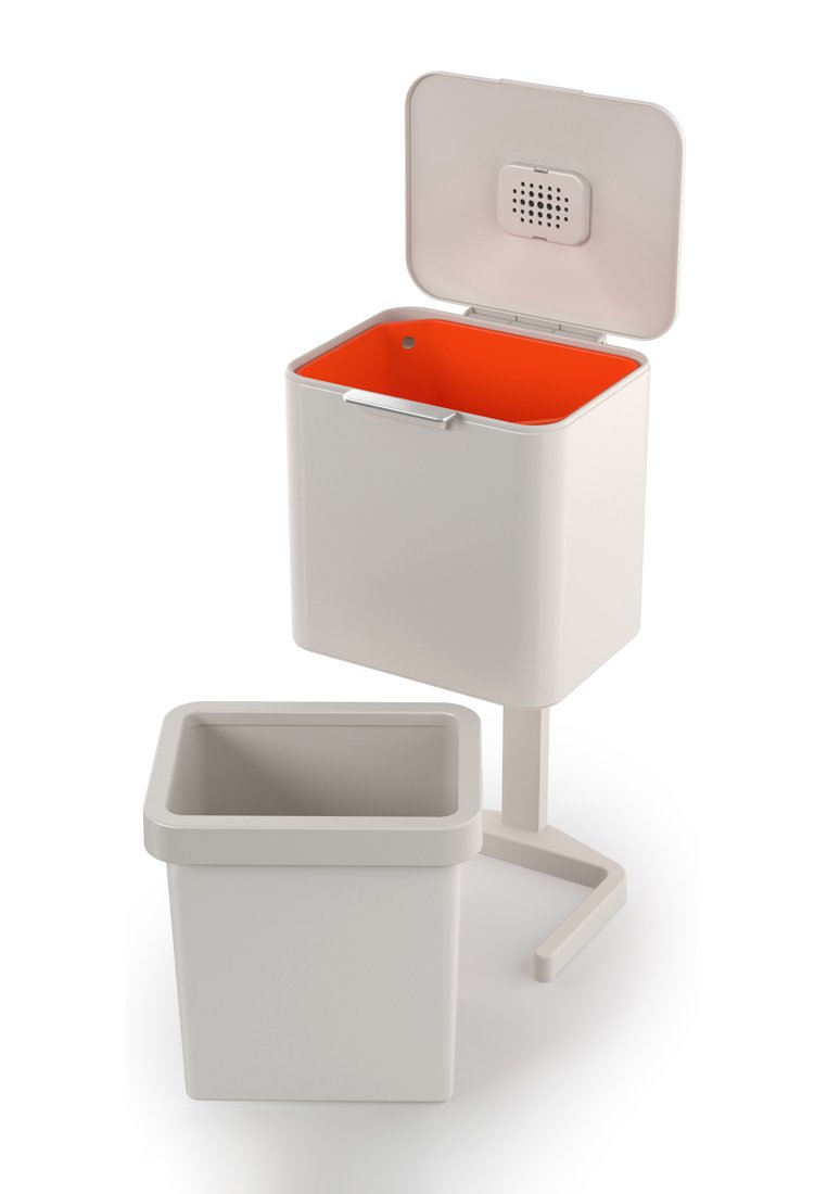 Weißer Abfalleimer mit orangefarbenem Inneren, ausgestattet mit einem klappbaren Deckel und einem belüfteten oberen Teil. Enthält einen herausnehmbaren Innenbehälter. Einfaches geometrisches Design.