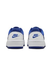 Kungligt blåa och vita Nike-sneakers med en slät läderöverdel, texturerad tyg-tunga och synlig branding på hälen. Platt gummisula.