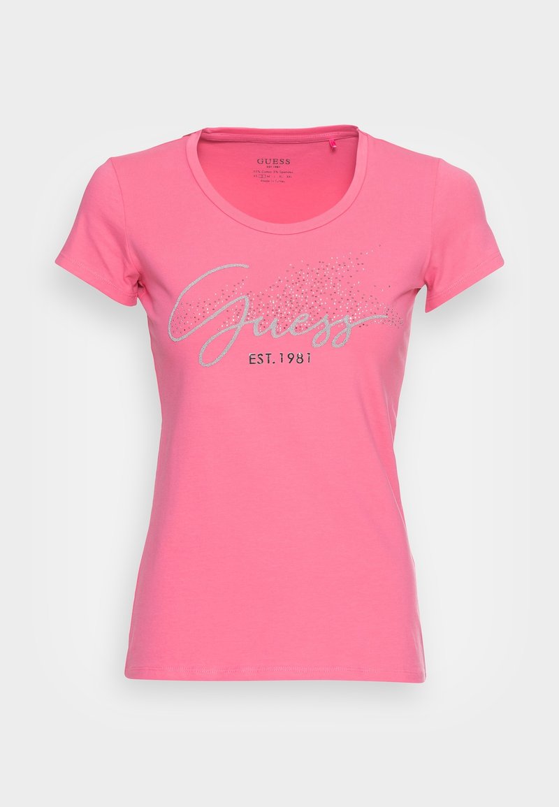 T-shirt en coton rose à manches courtes. Présente un logo en paillettes argentées "Guess" et "EST. 1981" dans un design de script décontracté.