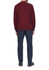 Roter Strickpullover mit strukturiertem Muster, gerippten Bündchen und Saum, kombiniert mit navyblauen Hosen und schwarzen Schuhen, von hinten betrachtet.