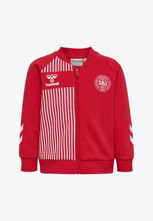 Czerwona kurtka na zamek błyskawiczny z białymi pionowymi paskami na lewej stronie z przodu, logo Hummel oraz emblemat Dansk Boldspil Union na prawej piersi.