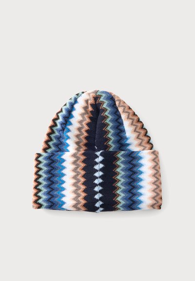 Bonnet tricoté avec motif en zigzag bleu, noir, blanc, marron et vert sur fond clair uni.