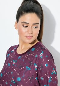 Chemise bordeaux à manches courtes arborant un motif céleste avec des accents teal, des yeux et des constellations, col rond et texture douce.