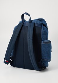Sac à dos en denim bleu marine avec un dos en mesh rembourré, des bretelles réglables, une poche latérale zippée et des accents cousus. Design compact et fonctionnel.