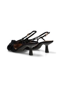 Tacones negros tipo slingback con correas finas, pequeños tacones cuadrados y detalles de volantes en la parte superior del zapato.