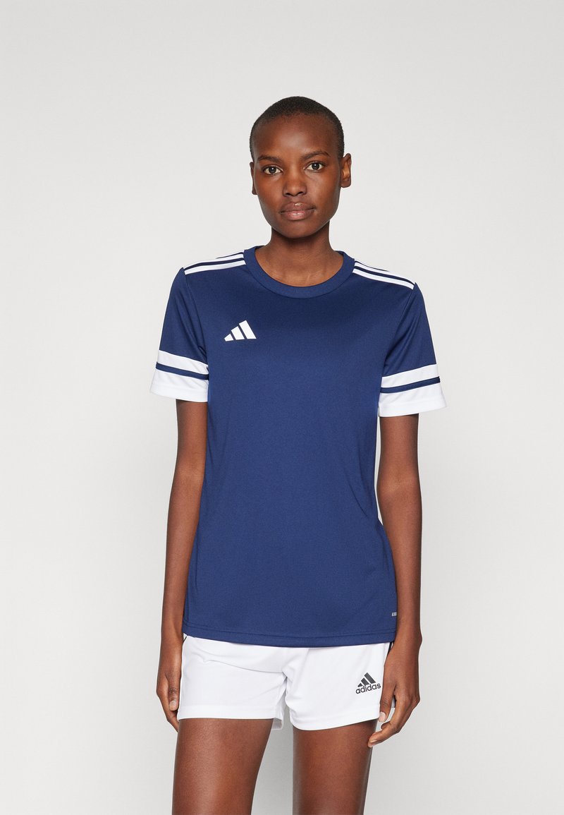 Marine atletisk t-skjorte med hvite detaljer, korte ermer, rund hals og Adidas-logo. Kombinert med hvite shorts med logo. Glatt stofftekstur.
