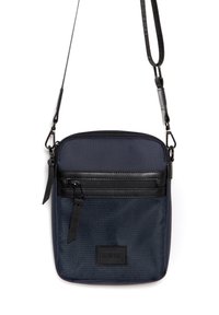 Námořnická modrá crossbody taška vyrobená z texturované látky s černými akcenty, obsahující zipovou přední kapsu a nastavitelné ramenní popruhy.