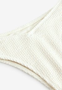 Teksturowany biustonosz bikini w kolorze off-white z falistym wzorem, z bezszwowym wewnętrznym wykończeniem i gładkim elastycznym wykończeniem dla wygodnego dopasowania.