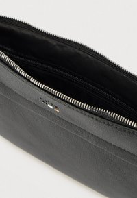 Μαύρο δερμάτινο πορτοφόλι με υφή, με ασημένιο φερμουάρ, που διαθέτει λείο εσωτερικό επένδυση και διακριτική λεπτομέρεια με το λογότυπο.