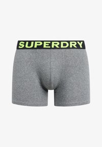 Graue gestreifte Boxer-Briefs mit einem schwarzen Bund, der "SUPERDRY" in leuchtend gelber Schrift trägt. Glatte Textur und enganliegendes Design.