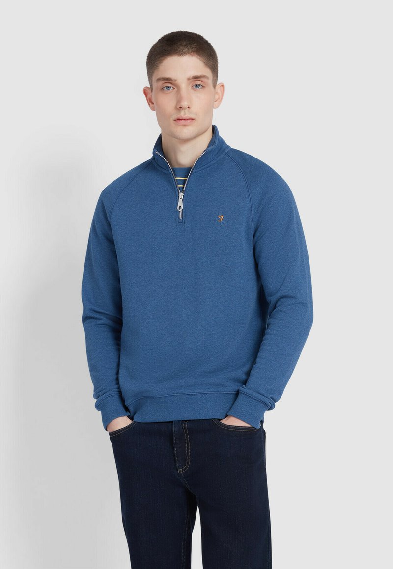Blue quarter-zip sweatshirt made of soft fabric with ribbed cuffs and collar. Features a small logo on the chest and a relaxed fit.