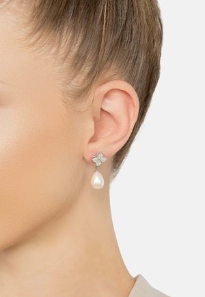 Sterling silver earrings with a butterfly design featuring small clear gemstones and a dangling pearlescent drop.