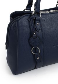 Borsa a mano in pelle blu navy con superficie testurizzata, rifiniture in metallo argentato, chiusura con zip e un'etichetta circolare decorativa con le iniziali.