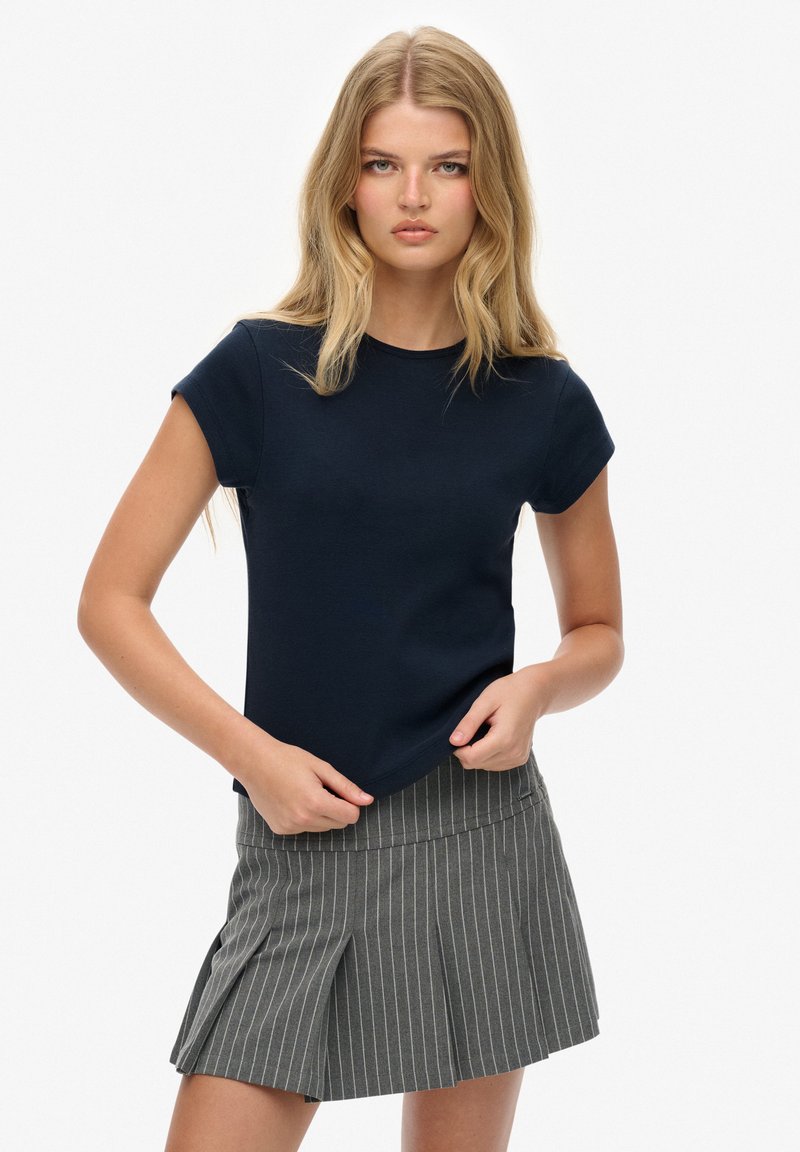 Marineblauwe katoenen t-shirt met korte mouwen en een ronde halslijn, gecombineerd met een grijze pinstripe rok met plooien en een getailleerde tailleband.