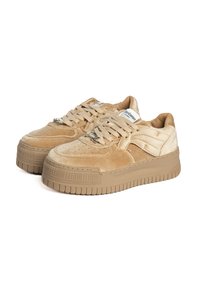 Sneaker in suede beige con suola spessa e testurizzata. Presenta un design con lacci, punta perforata e logo sulla linguetta e sul lato.