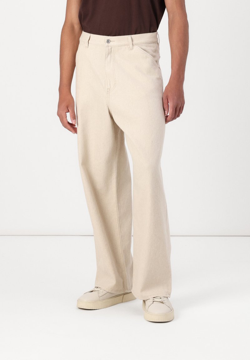 Beige wide-leg trousers made of denim, featuring a front button closure, side pockets, and a clean, textured finish.