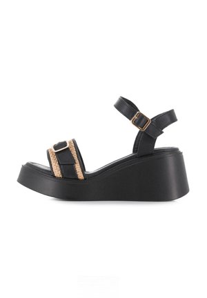 Sandalia cuña negra con tira tejida beige y hebilla en tono dorado. Presenta una parte superior de cuero suave y una suela de plataforma gruesa.