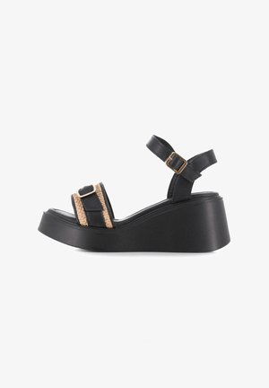 Sandalia cuña negra con tira tejida beige y hebilla en tono dorado. Presenta una parte superior de cuero suave y una suela de plataforma gruesa.