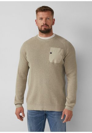 Beige gebreide trui met textuur en een ronde hals, voorzien van een lichtbeige borstzak met een donkere knop en een stoffen logodetail.