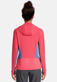 Chaqueta con capucha para mujer que presenta un frente rosa brillante y paneles laterales azules; tejido texturizado con mangas ajustadas; diseño transpirable.