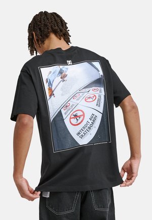 Czarny bawełniany t-shirt z dużym nadrukiem na plecach przedstawiającym skateboardzistę i znaki zakazu jazdy na deskorolce, z białymi akcentami.