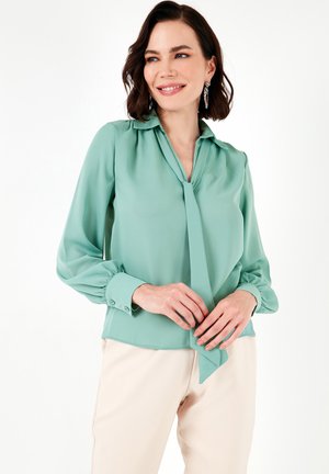 Mint green blouse with a tie neck, long sleeves, and buttoned cuffs. Soft fabric with a smooth texture and a relaxed fit.