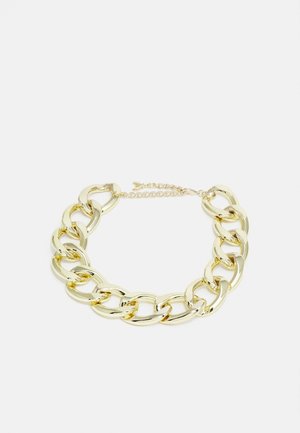 Dikke gouden ketting met grote ovale schakels en een verstelbare sluiting op een lichte achtergrond.