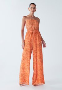Oranger blumiger Jumpsuit mit schulterfreiem Design, gerafftem Oberteil, taillierter Gürtellinie und weitem Bein. Leichtes, atmungsaktives Material.