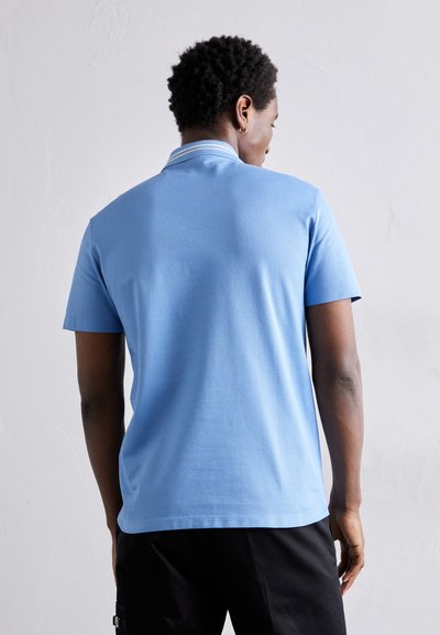 Camisa polo de manga curta em algodão azul claro com colarinho canelado e detalhes de costura subtis. Design simples com uma textura suave.