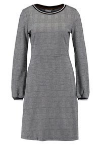 Svart och vit rutmönstrad klänning med långa ärmar, rund hals, rynkade ärmar och kontrasterande krage. Slät tygstruktur.