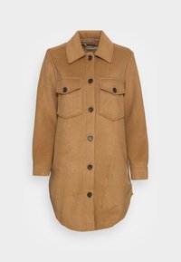 Brun ullblandad skjortjacka med spetsig krage, två bröstfickor och sex bruna knappar som går ner fram. Slät textur.