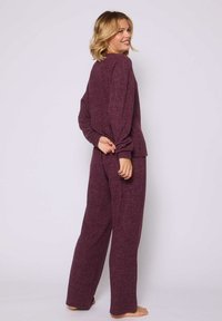 El conjunto de ropa de estar marl burdeos cuenta con una blusa de manga larga holgada y pantalones de pierna ancha, ambos con una textura suave y una silueta relajada.