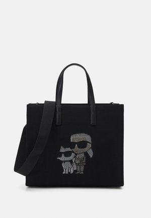 Black tote bag with dual handles and shoulder strap, decorated with rhinestone artwork of a person and a cat wearing sunglasses.
