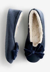 Navy blue slippers with soft faux fur lining, round toe, and a large velvet bow. Textured rubber sole for grip, featuring branding detail.