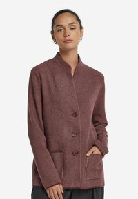 Burgundy stickad jacka med mandarin-krage, fyra framknappar, två sidofickor och en strukturerad tyg.