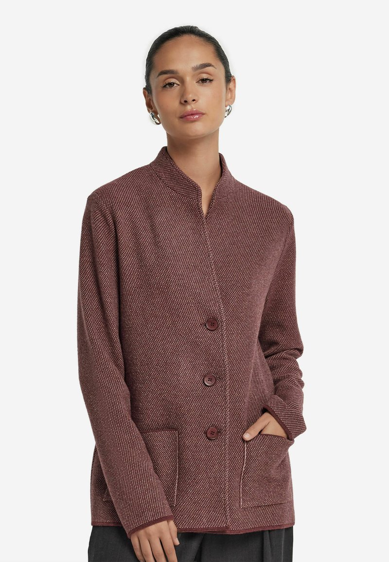 Burgundy stickad jacka med mandarin-krage, fyra framknappar, två sidofickor och en strukturerad tyg.