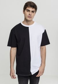 Black and white oversized t-shirt with a round neck, short sleeves, and a vertically split design, made from soft cotton fabric.