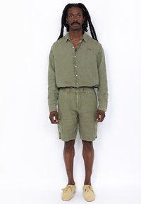 Olijfgroen shirt met knopen en borstborduursel, gecombineerd met bijpassende cargoshorts met zijzakken en een ontspannen pasvorm.