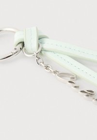 Ασημένιος μεταλλικός μπρελόκ συνδεδεμένος με λουράκι από δέρμα σε ανοιχτό μέντα πράσινο χρώμα, με ασημένια αλυσίδα και μεταλλικό γούρι με την επιγραφή "love" σε καλλιγραφικό στυλ.