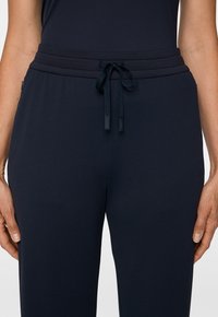 Granatowe dresy wykonane z miękkiej, teksturowanej tkaniny z elastycznym pasem, z wiązaniem na sznurki i bocznymi kieszeniami.