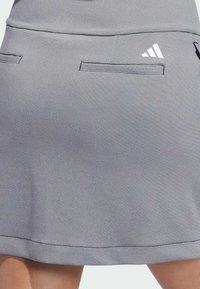 Sivi sportski šorts s dva stražnja džepa, glatkom teksturom i suptilnim šavovima. Sadrži bijeli logo na stražnjoj strani.