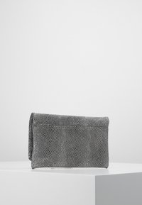 Kopertówka w czarno-białym teksturowanym materiale, o gładkim, prostokątnym kształcie z klapką zapinającą i subtelnym wzorem na powierzchni.