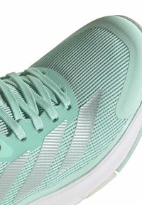 Gros plan sur une chaussure de sport vert menthe avec une tige en tricot texturé, des lacets assortis et une semelle blanche en caoutchouc.