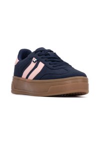 Sneaker blu navy in tessuto, con strisce rosa, colletto imbottito e suola in gomma marrone con un motivo testurizzato.