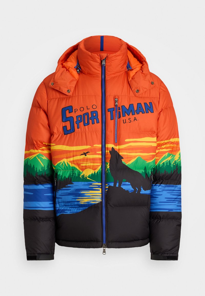 Veste matelassée orange avec des graphismes de montagne et de loup, section inférieure noire, fermeture éclair, capuche et accents bleus sur le col et le logo.