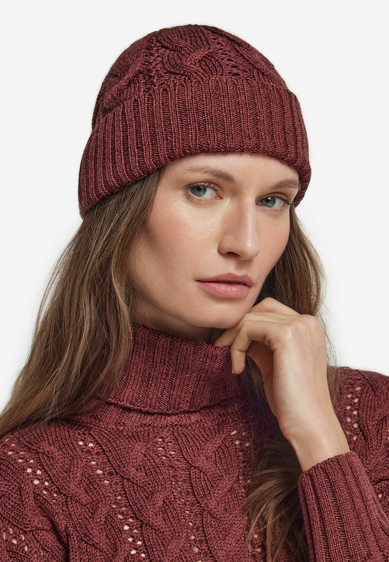 Bordowa dzianinowa czapka z wzorem warkoczowym i ściągaczem. Posiada dopasowany styl, zestawiona z dopasowanym golfem o tym samym wzorze warkocza.